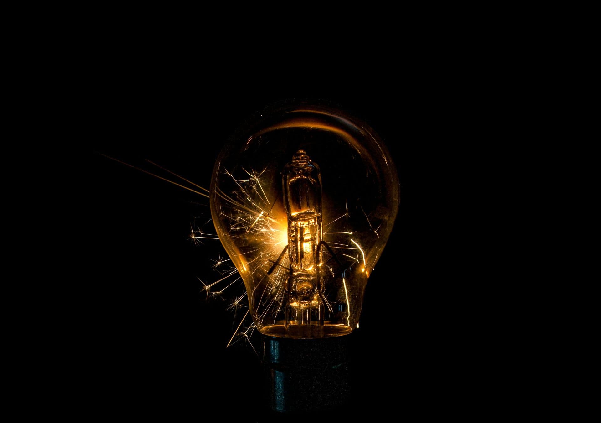 A glowing light bulb sparking against a dark background