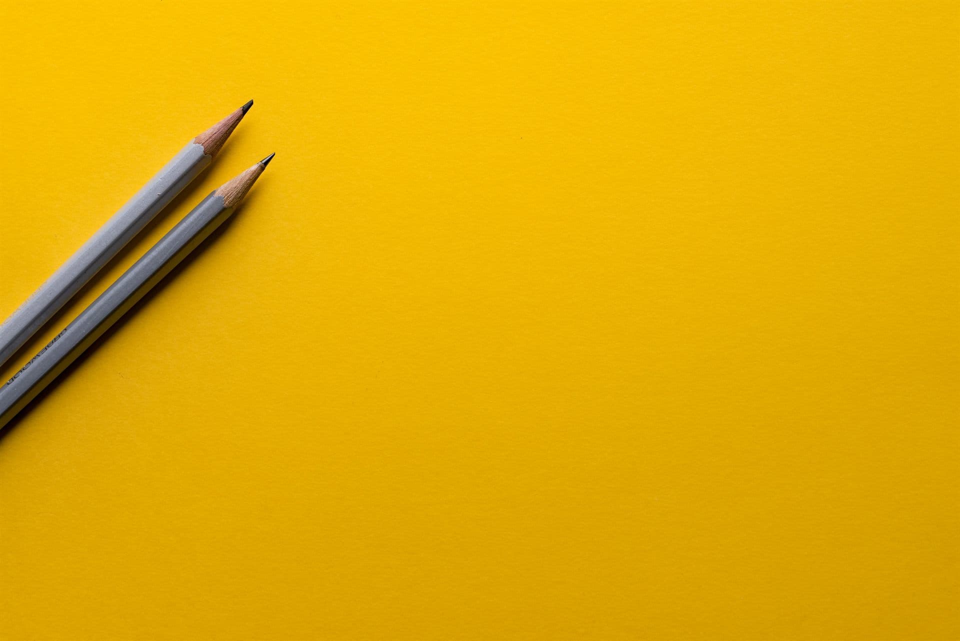 Two sharpened pencils on a yellow background