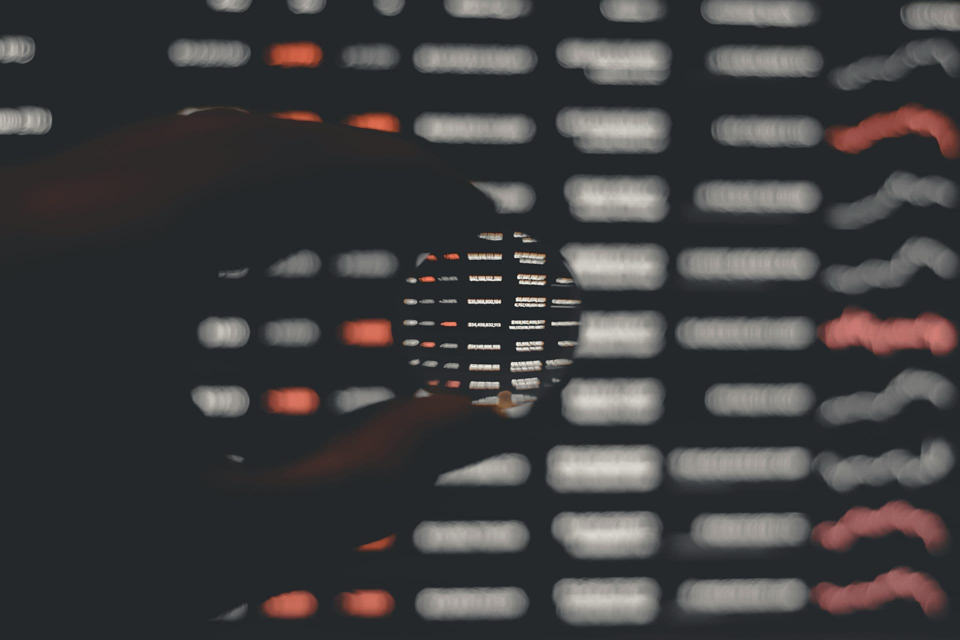 A magnifying glass enlarging rows of data on a dark screen